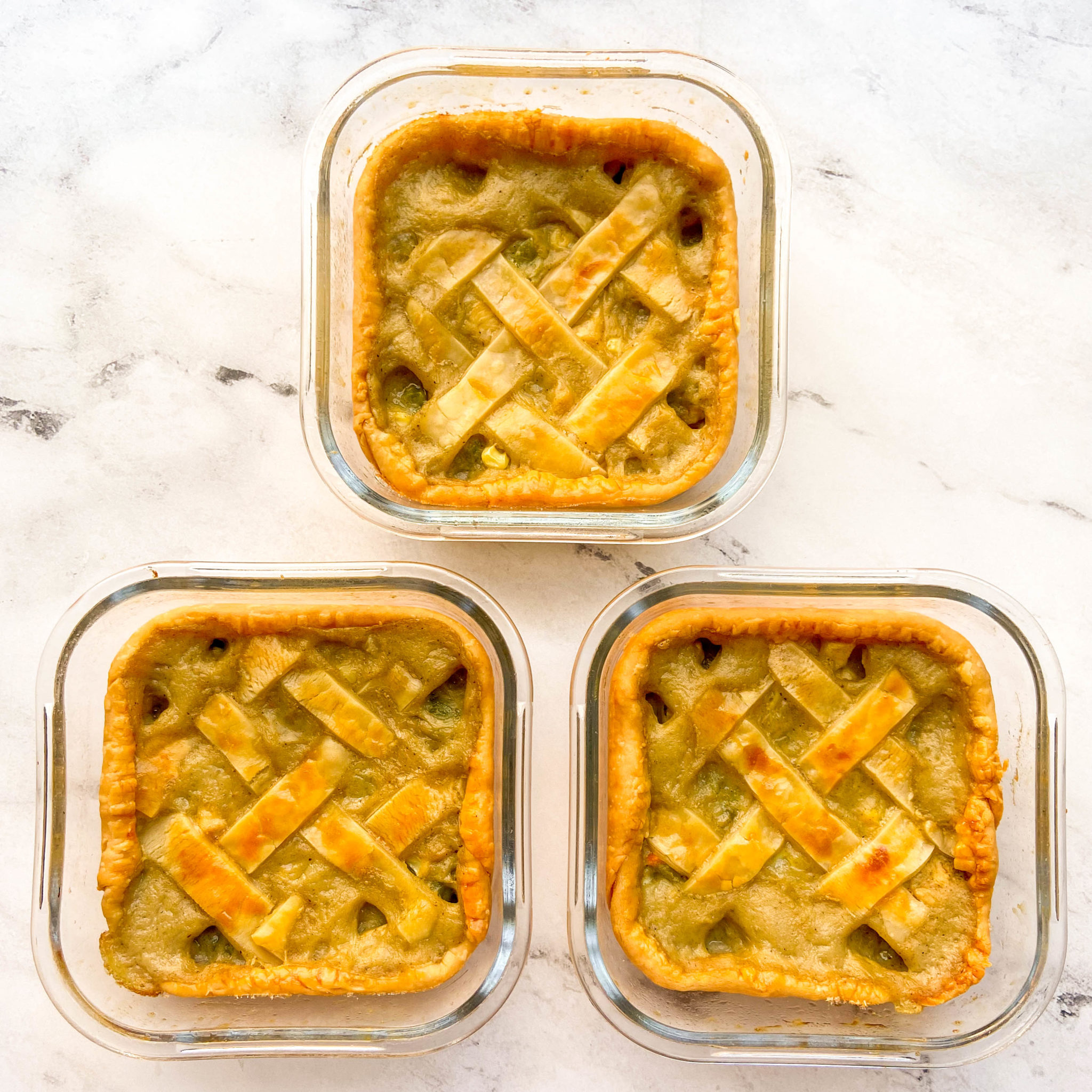 Three square containers in a triangle formation that each contain individual chicken pot pies