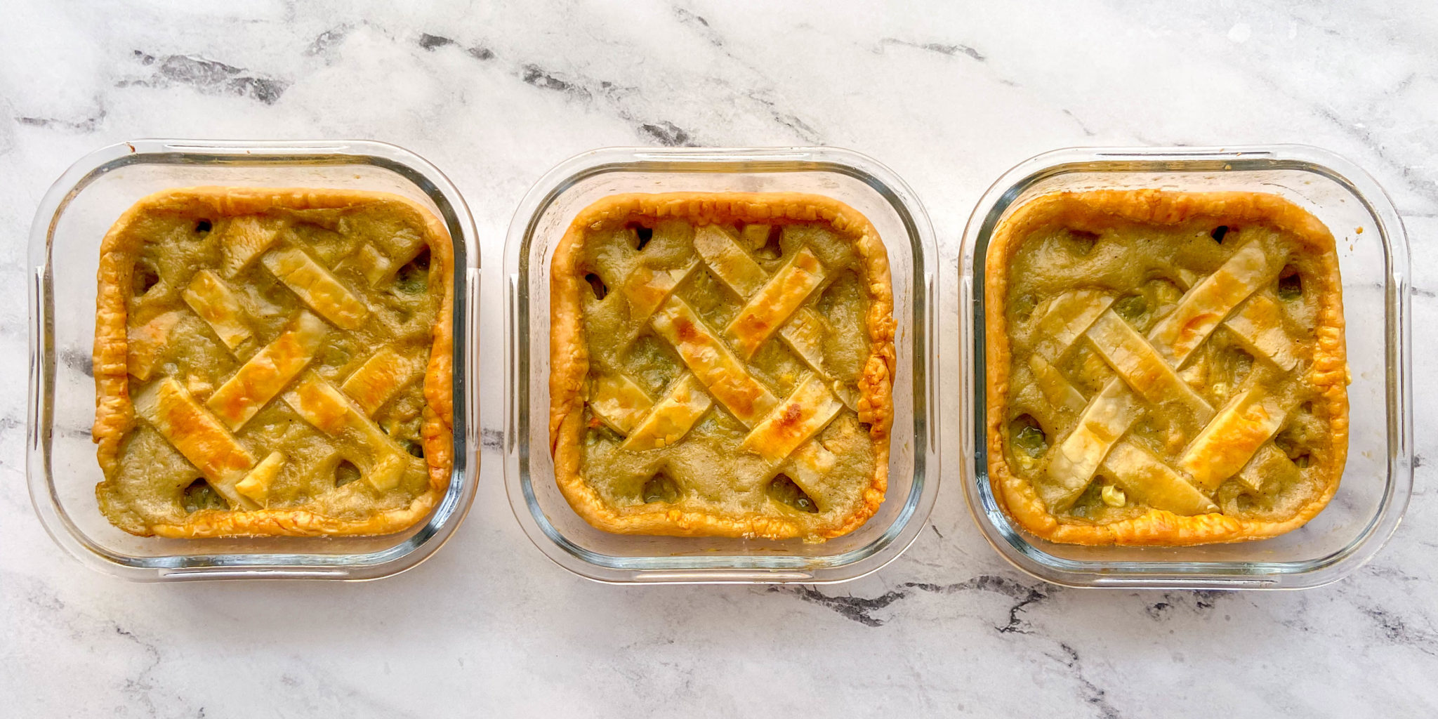 Three square containers in a row that each contain individual chicken pot pies