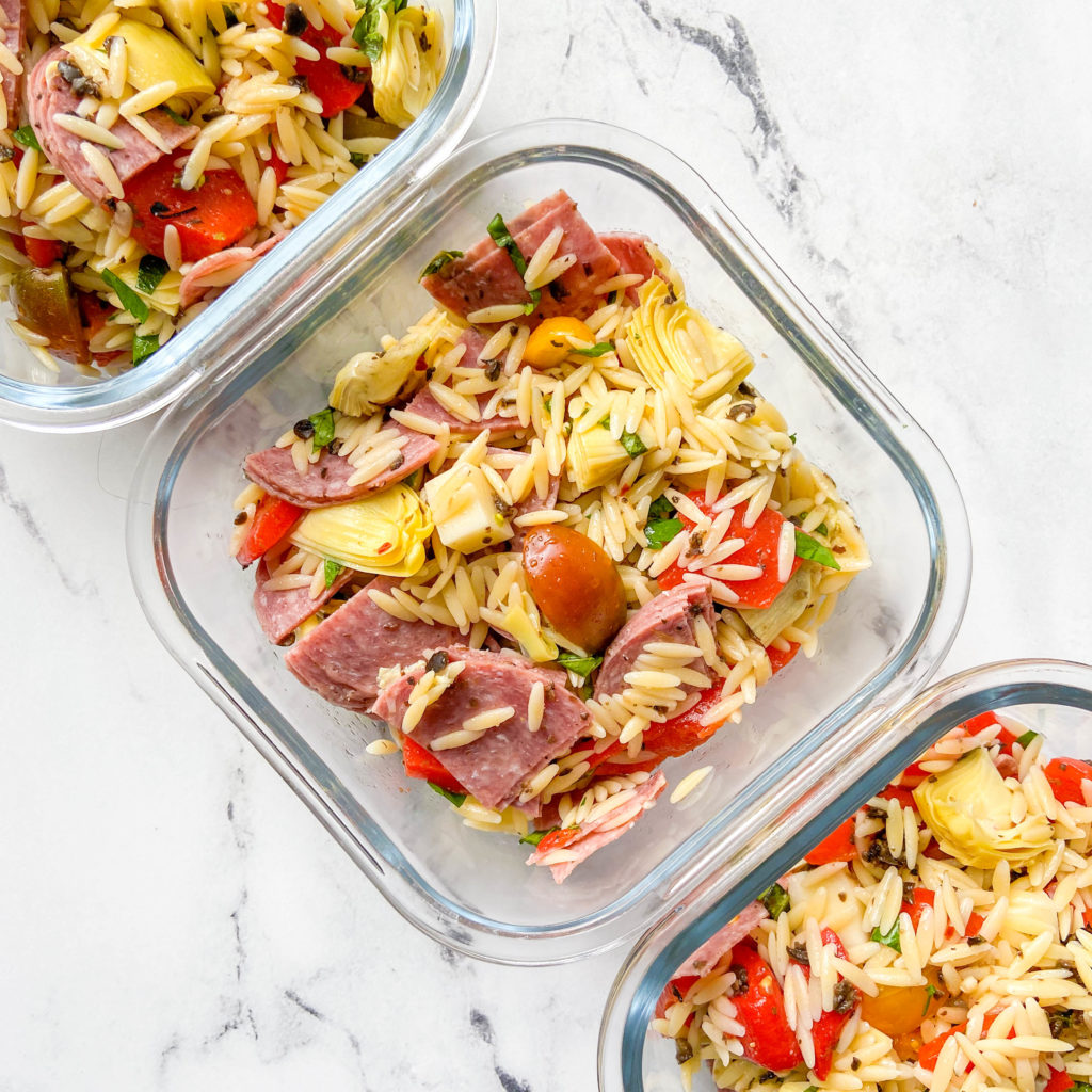 3 glass containers full of antipasto salad featuring orzo, tomato and sausage