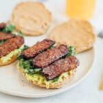 two breakfast sandwiches are shown with avocado and pieces of tempeh on top