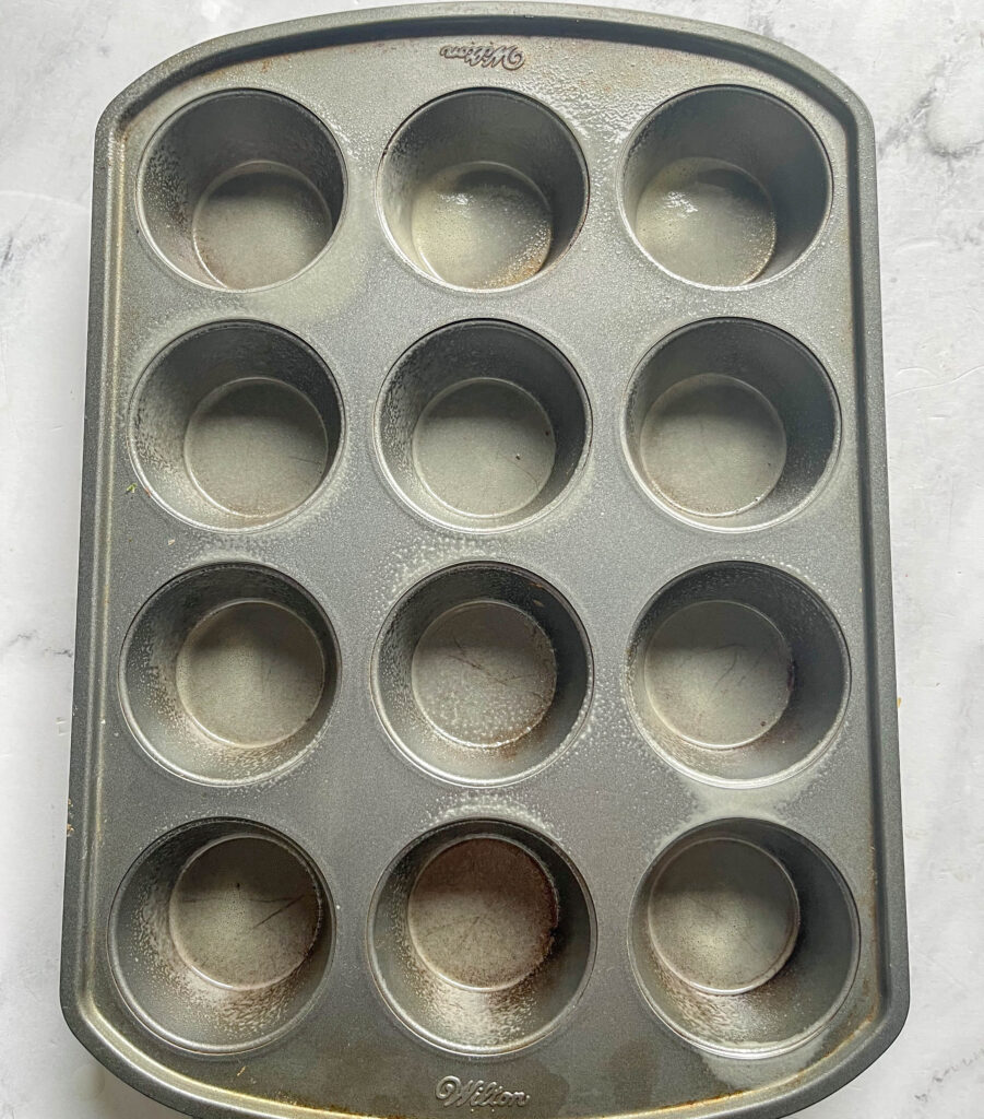 A muffin tin with 12 wells greased with cooking spray.