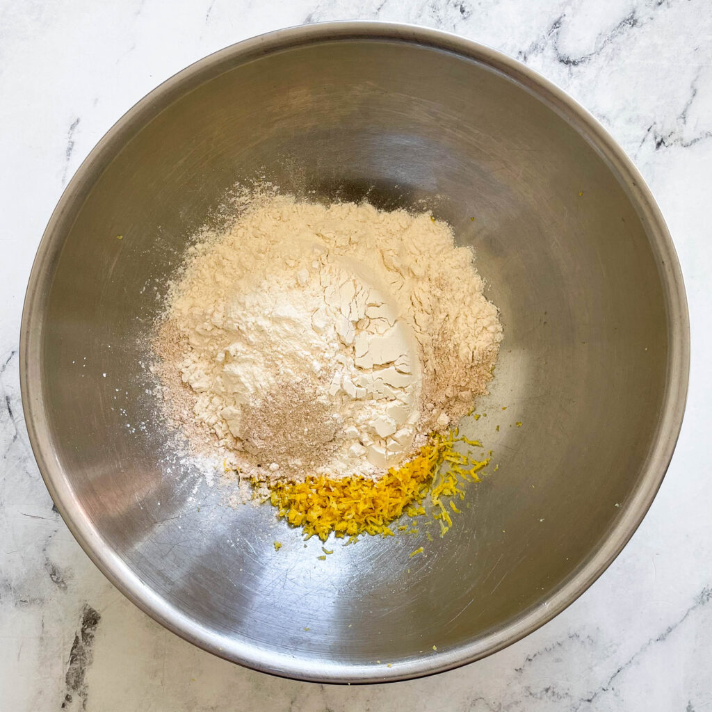 a metal bowl full of flour and lemon zest