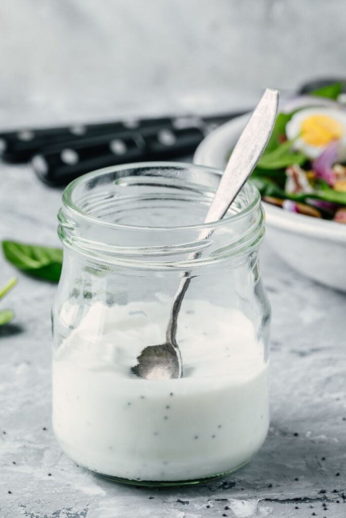 homemade ranch dressing in a glass jar with a spoon